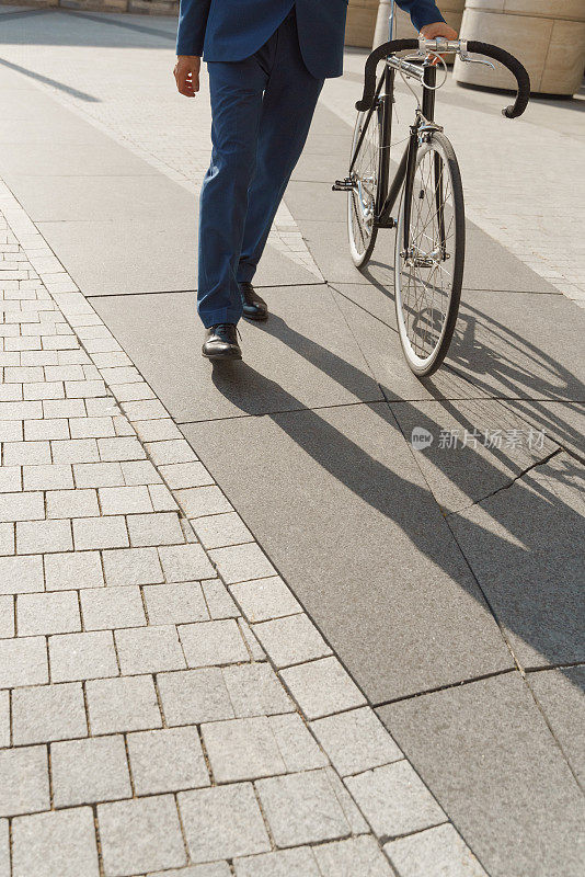 一个穿着蓝色西装的年轻人骑着现代自行车走在街上