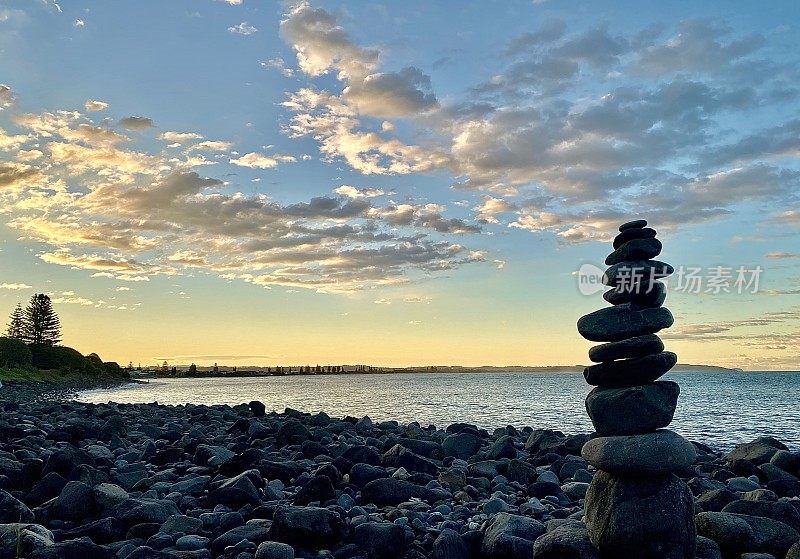 石头平衡:日落时的海滩岩石堆