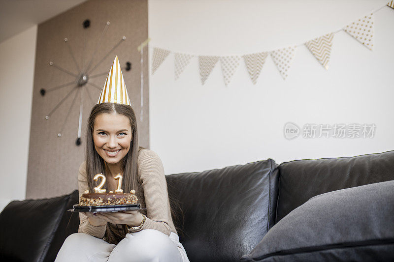 年轻漂亮的女人在家里用巧克力蛋糕庆祝她21岁的生日