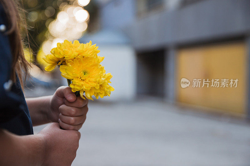 一个年轻的女孩手捧一束黄色的花