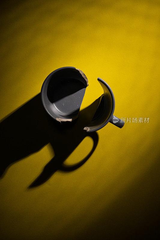 破碎的杯子顶部视图的黄色背景与硬阴影