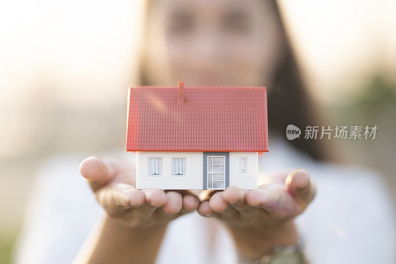 一位年轻女子正在展示一所房子的模型。