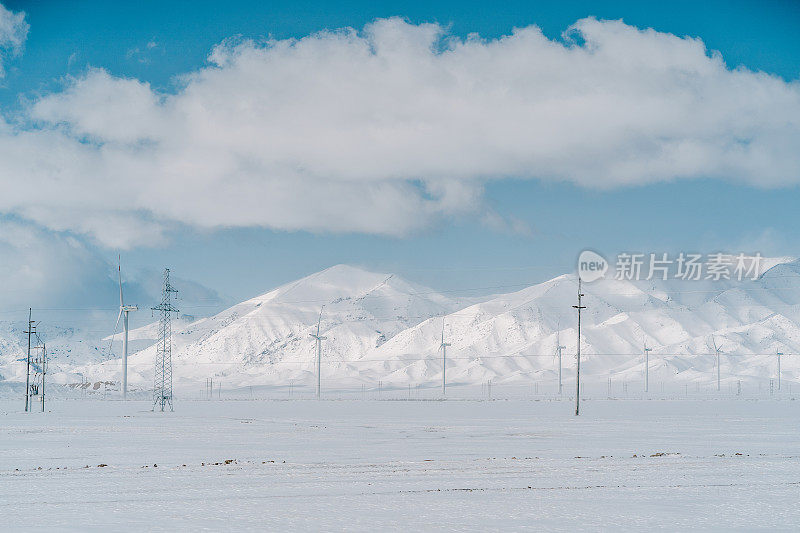电线杆矗立在中国新疆的雪原和山脉之间