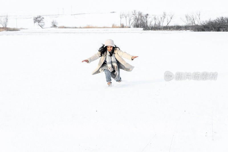 年轻女子在冬天的雪地里玩得很开心