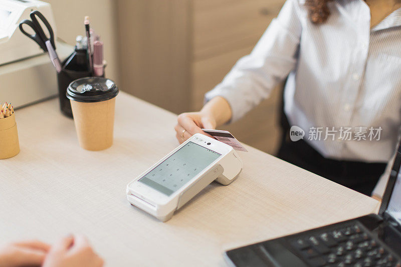 零售支付。年轻女子在家具店用信用卡付款。餐桌上的收银员为顾客服务。零售购买。小生意。事务处理。买家在商店