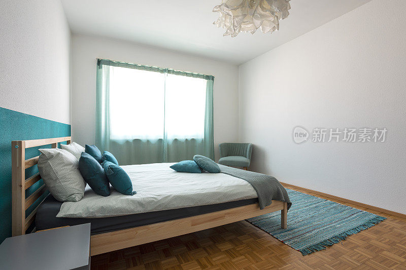 卧室里有木床，床单上还有很多枕头。房间有柔和的颜色和白色的墙壁