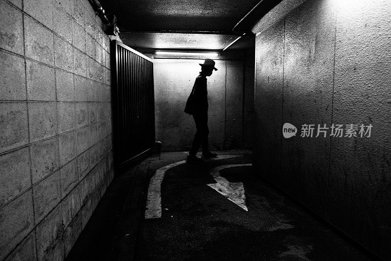 一个男人的剪影走在黑暗的通道里