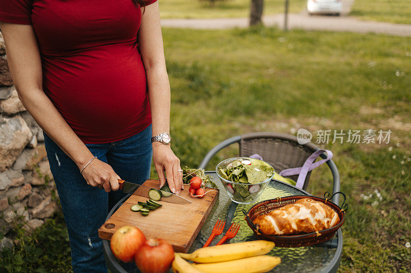美丽的孕妇在大自然中准备新鲜蔬菜沙拉