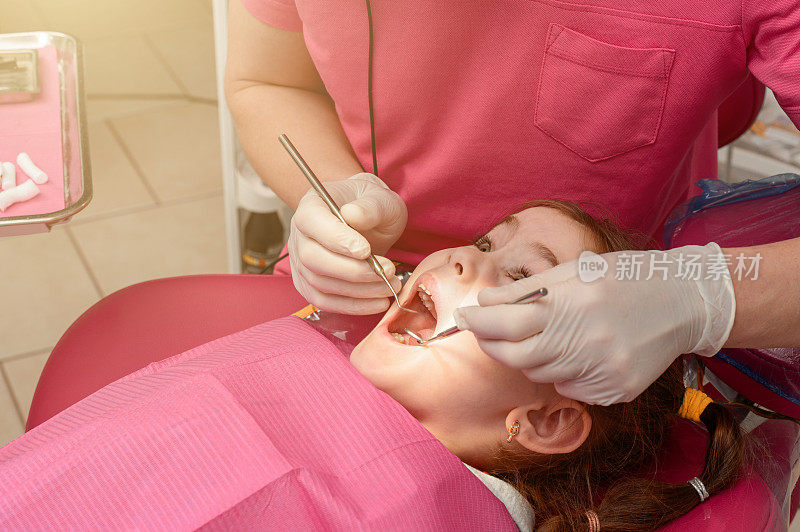 在一个治疗乳牙的孩子，一个小女孩去看牙医，检查和治疗牙齿。