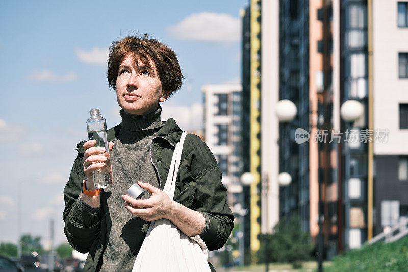 一个女人正在城市街道上喝水