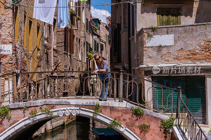 女人微笑着站在威尼斯的一座桥上