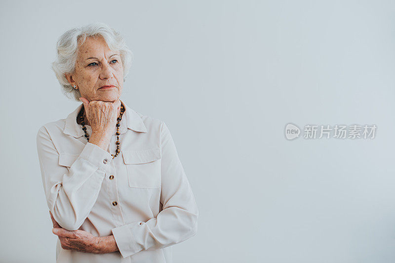 深思熟虑的高级妇女画像，手放在下巴上