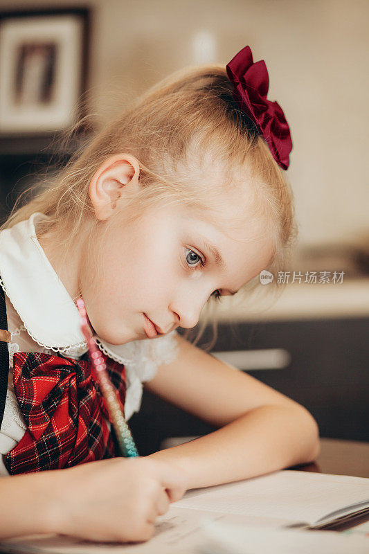 一个穿着校服的小女孩正在家里做作业
