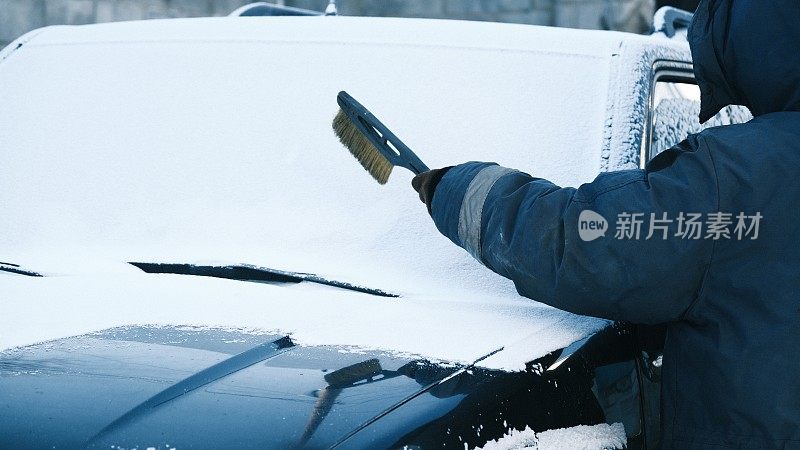 降雪后，一名妇女正在清洗家用汽车