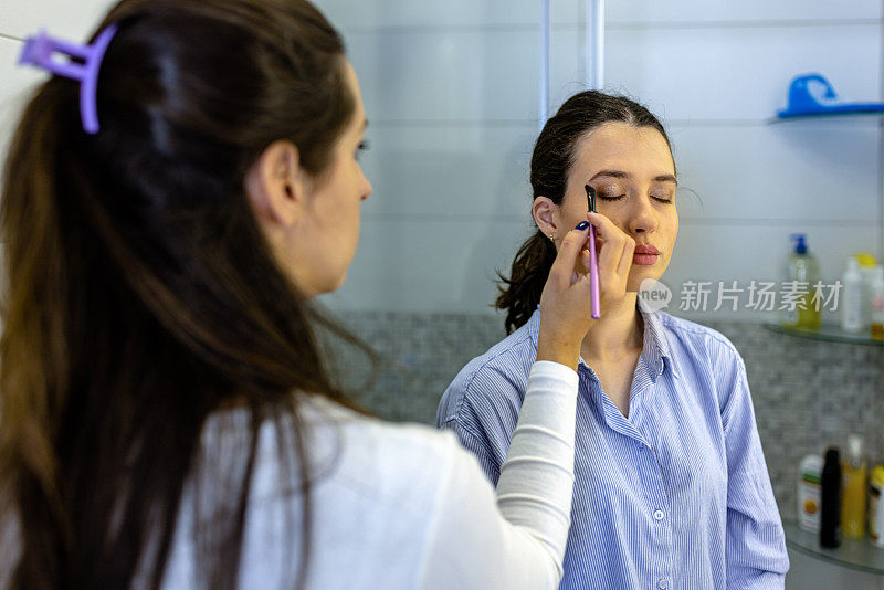 图为，一名女子正在家庭浴室接受女化妆师的面部护理。