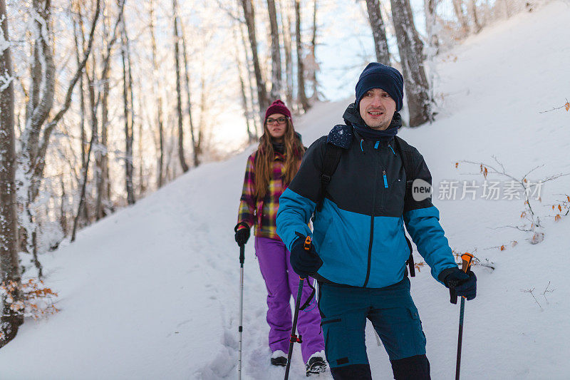 年轻的男性徒步旅行者和他的女性朋友一起从雪山小径上爬下来