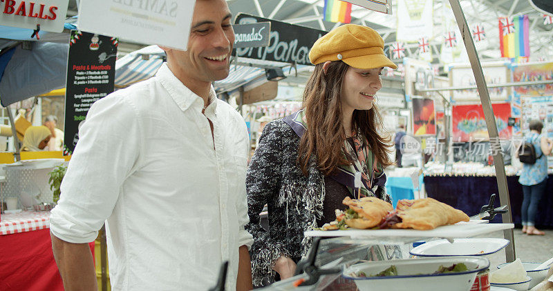 微笑的游客在伦敦市场购买食物