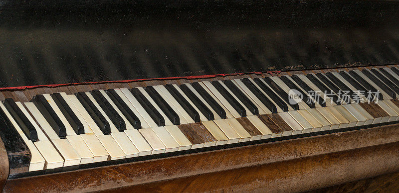 一架旧钢琴的琴键的特写，放在窗户旁边，早上从阳光中获得温暖。最悦耳的乐器