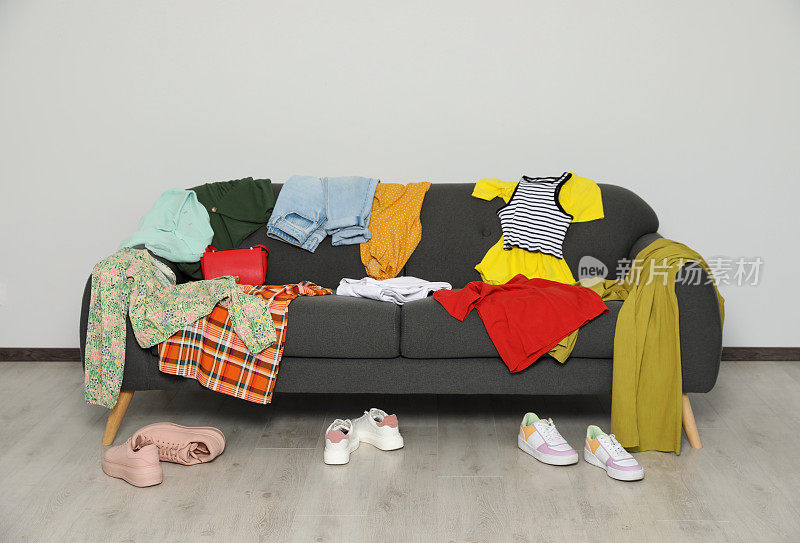 沙发上凌乱的一堆衣服，客厅里的鞋子
