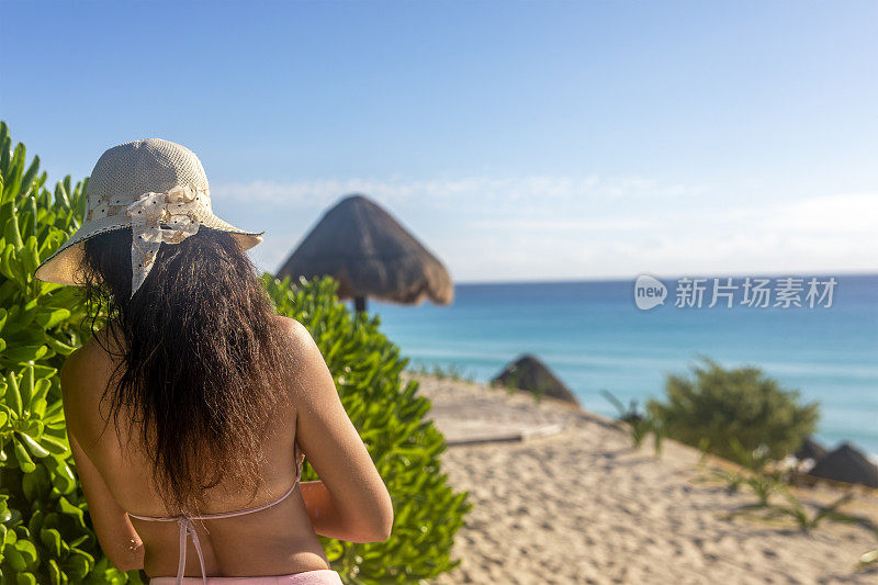 墨西哥坎昆酒店区海豚海滩上戴着帽子的性感女人。这是一个热带天堂般的海滩，白色和金色的加勒比海沙滩，非常受游客欢迎。