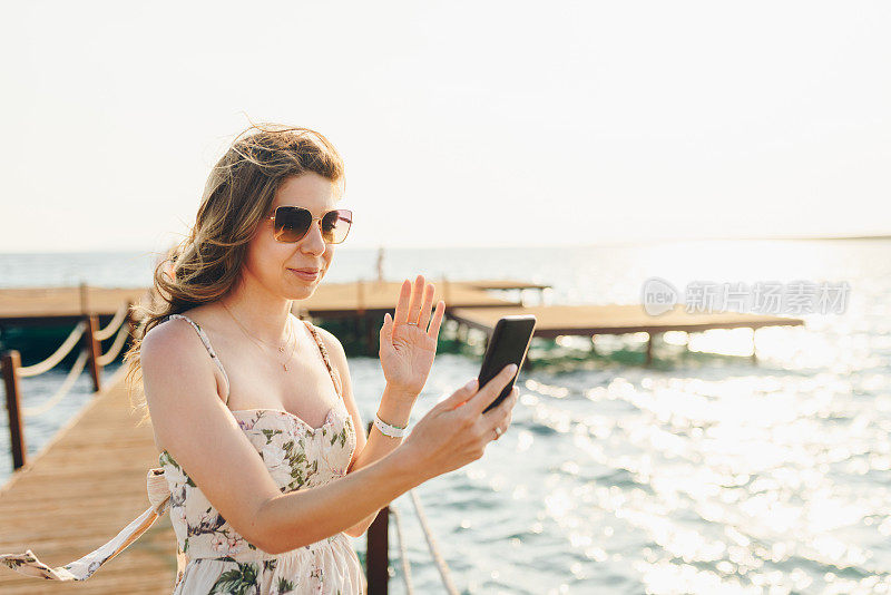 时尚女性在海边使用智能手机。暑假