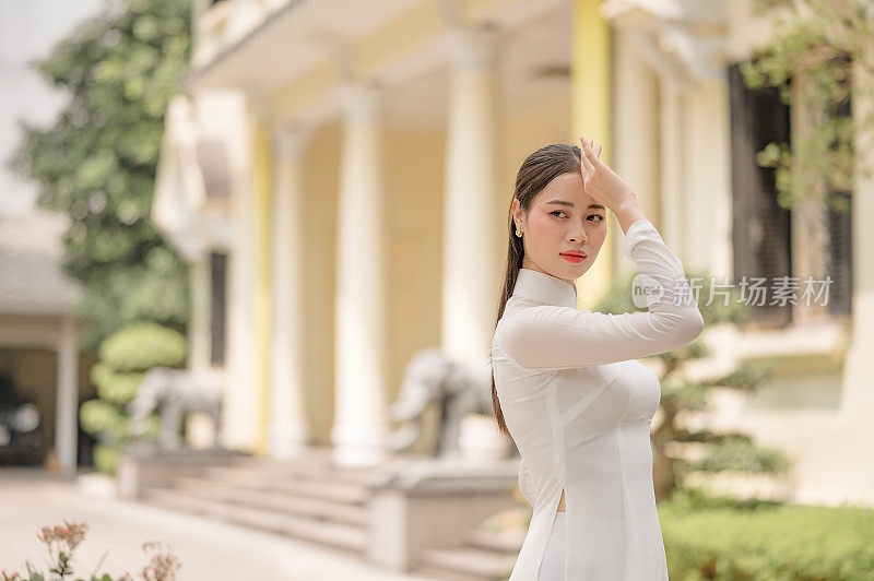 快乐的越南女孩穿着传统的白色敖代服装，戴着越南帽子