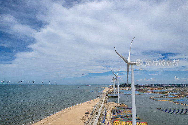 在海边阳光明媚的海滩上，风力涡轮机的鸟瞰图