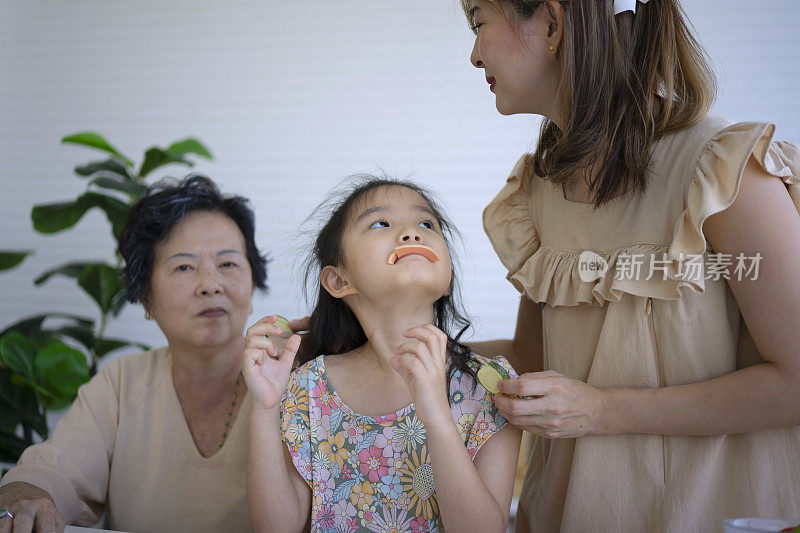 奶奶、妈妈和孙女在厨房准备食物。