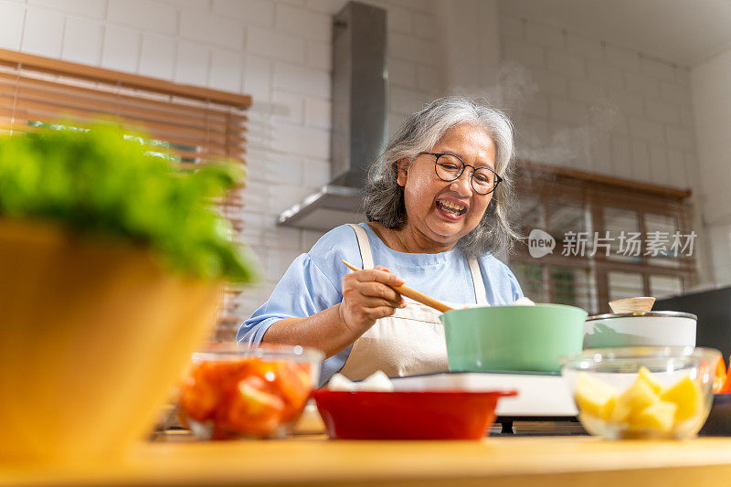 亚洲老年妇女在厨房做饭。