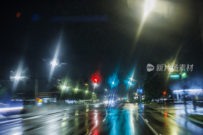 晚上在小镇潮湿的道路上开车。暴雨下模糊了灯火通明的街道。在佛罗里达州坦帕市的风暴边缘之后，道路的POV