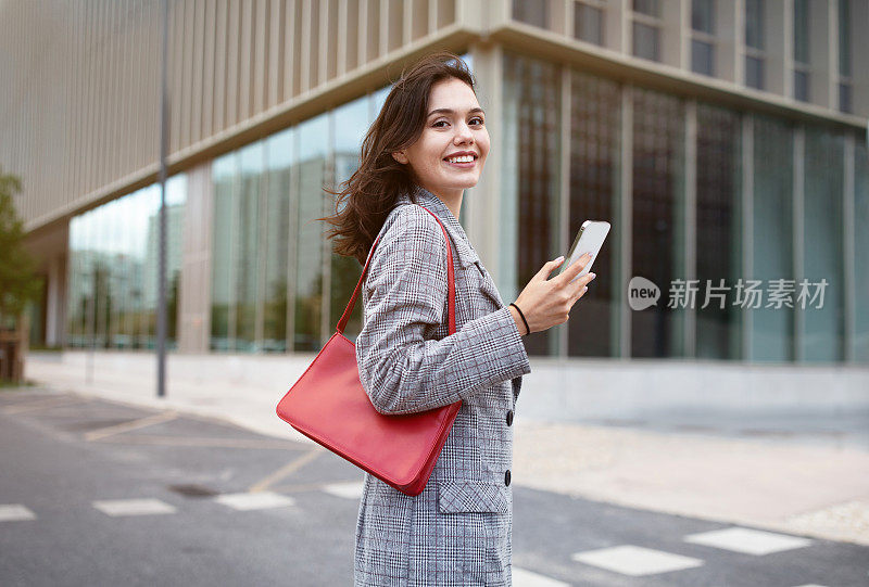 快乐的企业家女士用手机在市区户外散步