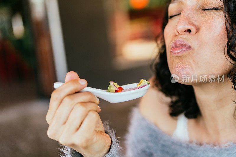 拉丁裔成年女性正在品尝酸橘汁腌鱼