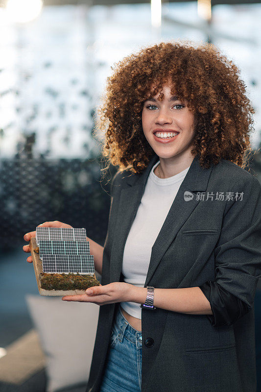 办公室里带着太阳能板模型的微笑女商人特写。