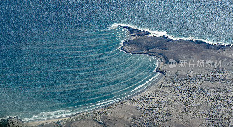 几组太平洋海浪撞击一小块陆地，造成波浪弯曲。下加利福尼亚南部，墨西哥。波变浅。