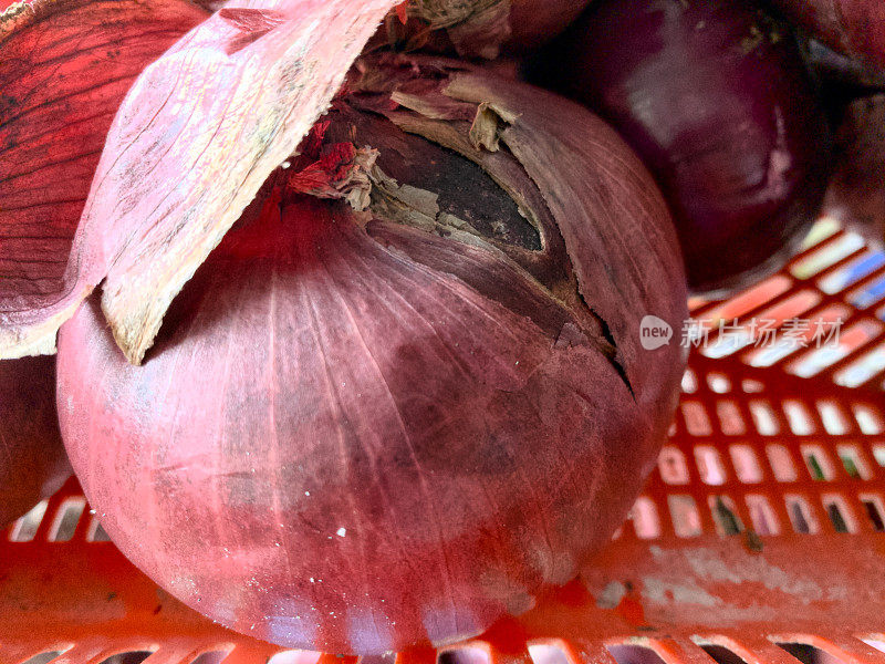 一个充满活力的特写镜头捕捉到了红色篮子里的红洋葱浓郁的深紫色。