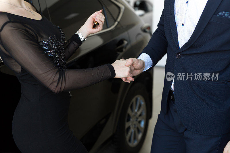 汽车销售员在车展上给新车主或客户钥匙的特写