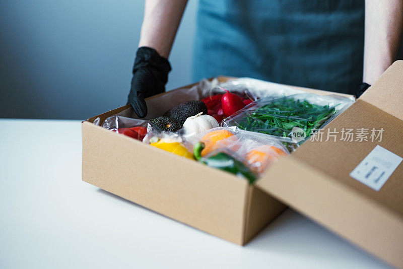 近距离的女性手打开包装盒与新鲜的蔬菜和水果