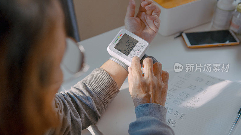 老年人检查血压，在家里的笔记本上记录血压数字。