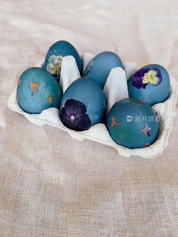 自然染色的青蓝压花复活节彩蛋鸡蛋盒在中性米色桌布背景。手工工艺，天然装饰。