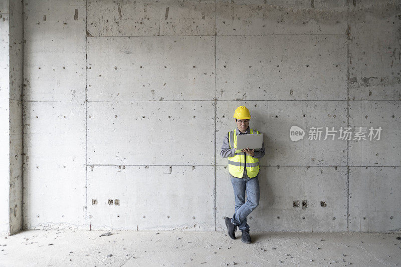 一名亚洲男性工程师在建筑工地使用平板电脑