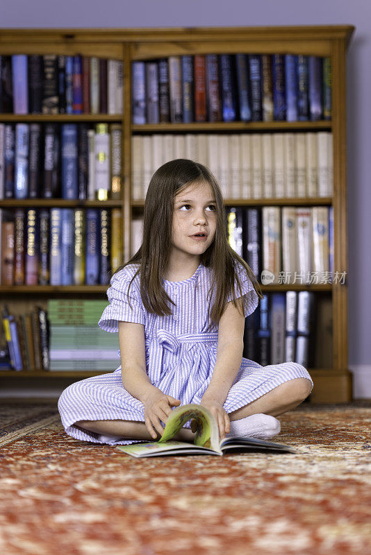 七岁的小女孩坐在地板上看书