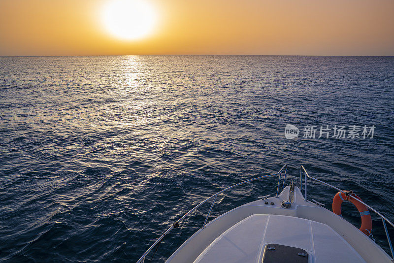 日出或日落，在海洋中帆船划船，海洋橙色的天空和蓝色的水