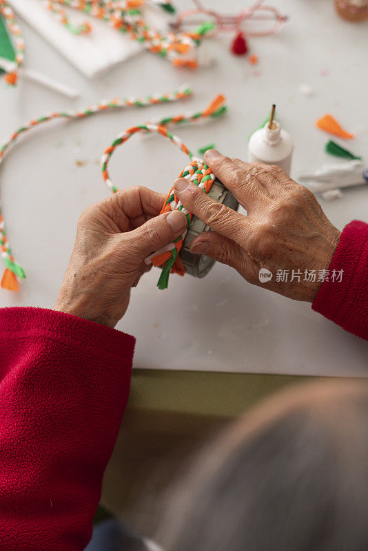 一位老妇人的手正在用材料制作工艺品