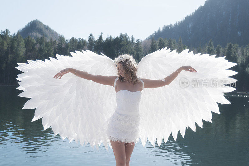 装扮成天使的女孩出现在湖的背景上