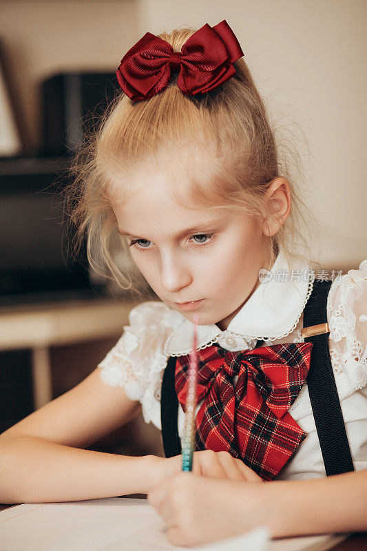 一个穿着校服的小女孩用左手在笔记本上写字，在家做作业
