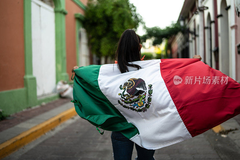 一个中年妇女举着墨西哥国旗走在街上