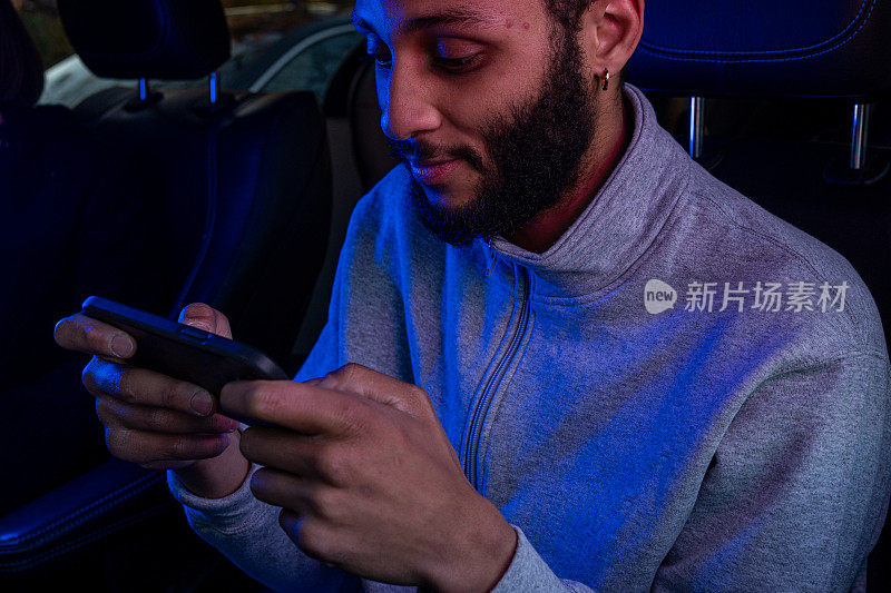 高大年轻的非洲裔男子水平拿着智能手机在市中心玩电子游戏