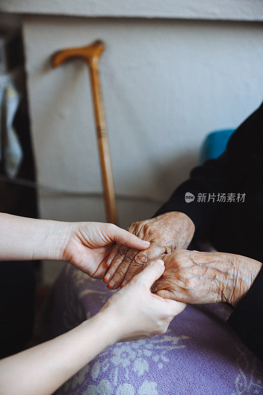 老女人的手牵着年轻女人的手，伸出援手，照顾老人的理念。