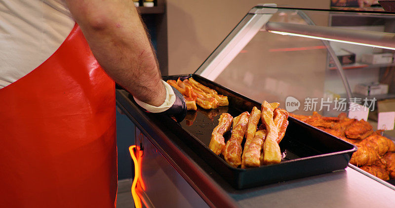 肉贩的手把肉放在商店展示柜的托盘上。