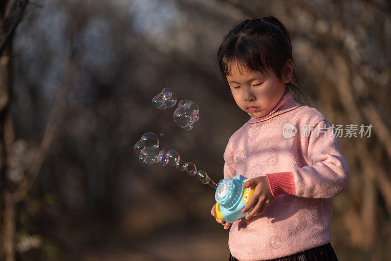 一个中国小女孩正在梅林里玩泡泡玩具